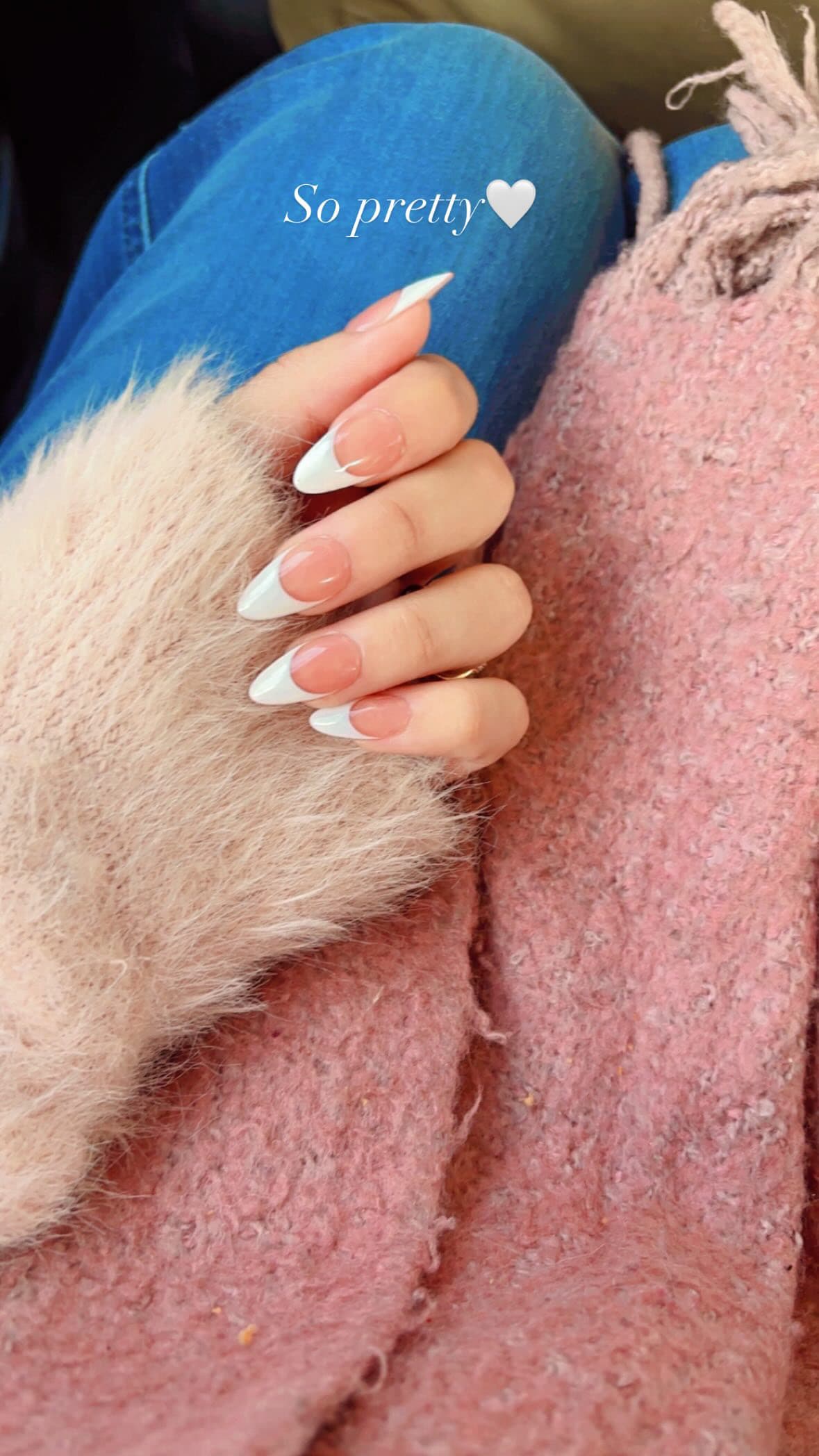 A white french tip set on long almond nails, worn